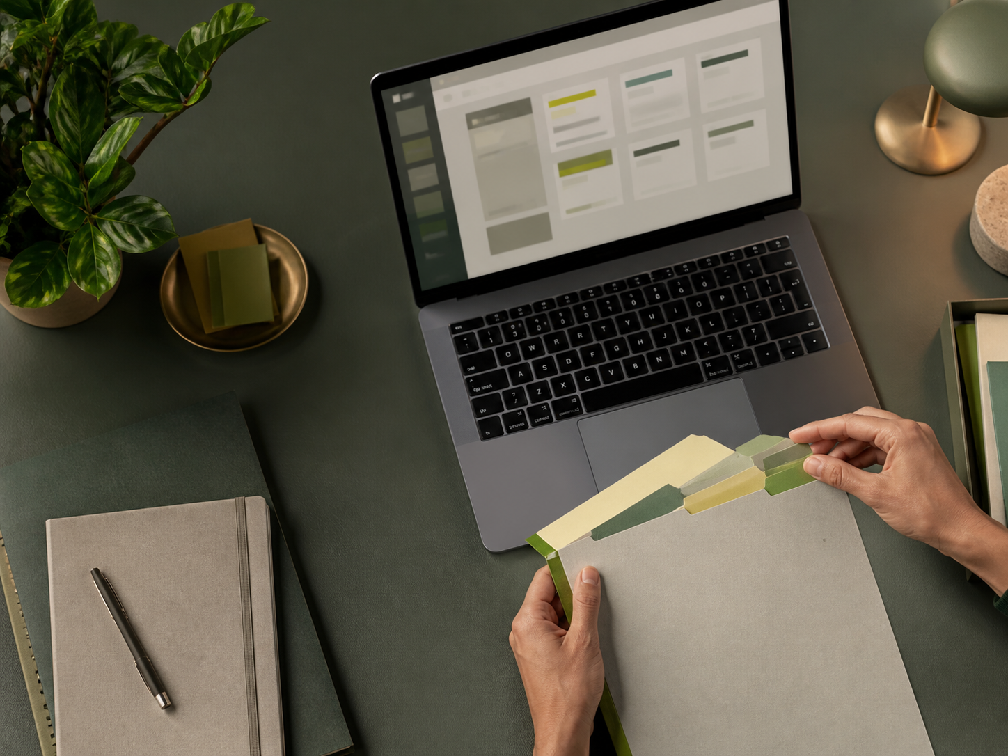 A person reviewing organized paper files beside a laptop